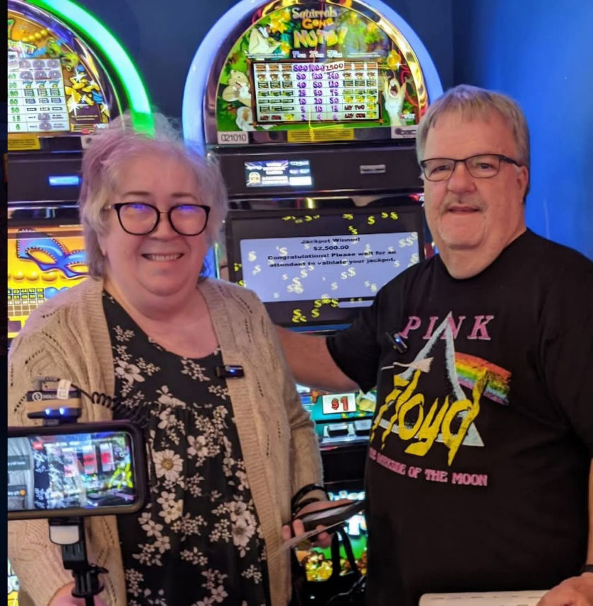 A man stands next to a jackpot with his wife.